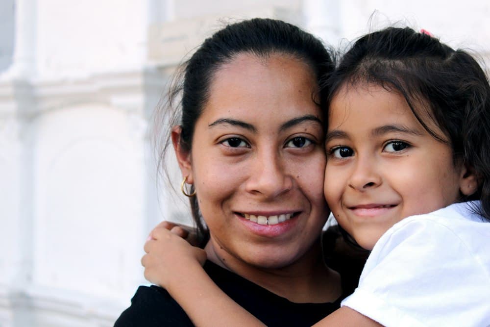 Una madre y su hija abrazadas, sonriendo